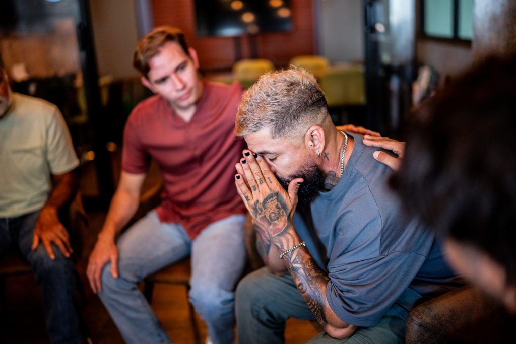 mature man being comforted in a group therapy at mental health center